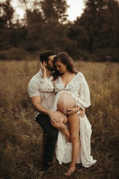 a pregnant woman is holding her husband's belly in the middle of a field