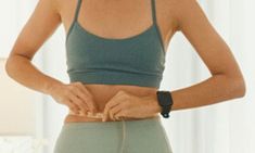 a woman is holding her stomach in front of the camera while wearing a sports bra