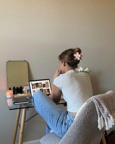 a woman sitting on a chair with her laptop computer in front of her, she is looking at the screen