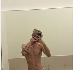 a shirtless man taking a selfie in the mirror