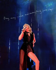 a woman in a black dress on stage with her legs spread out and holding a microphone