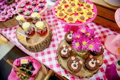 a table topped with cakes and cupcakes on top of wooden slices covered in flowers