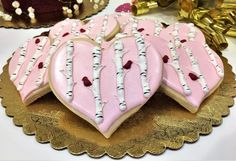 heart shaped cookies decorated with pink and white frosting on a gold platter next to other desserts