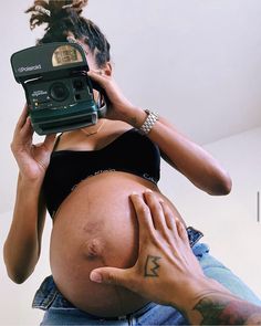 a pregnant woman taking a selfie with her camera in front of her face and hands