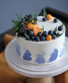 a white cake topped with blueberries and oranges