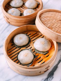 two wooden steamers filled with dumplings on top of a marble counter