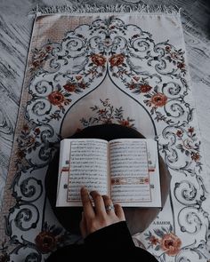 a person reading a book on top of a rug