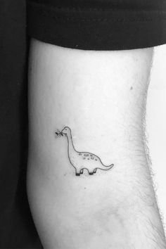 a black and white photo of a small dinosaur tattoo on the side of a man's leg