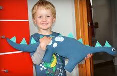 a young boy holding up a stuffed dinosaur