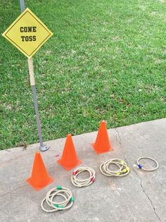 some orange cones are on the sidewalk near a sign that says cone tosses and ropes