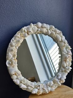 a mirror that is sitting on top of a wooden table with seashells in it