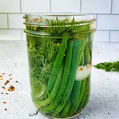 a jar filled with green beans and herbs