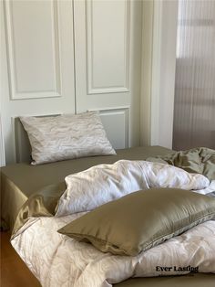 an unmade bed with several pillows on it