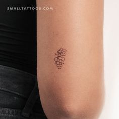 a woman's arm with a small tattoo of grapes on the back of it