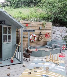 there is a dog that is standing in front of a shed with toys on the deck