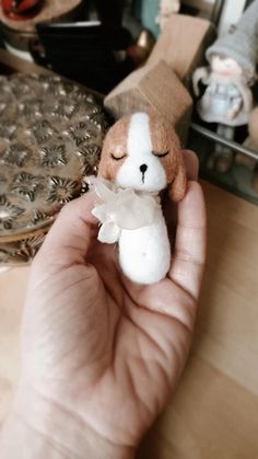 a hand holding a small stuffed animal in it's left hand on a table