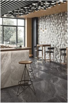 a bar with stools and tables in front of a large window that has an intricate pattern on it