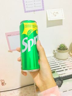 a person holding up a can of sprite soda in front of a white wall