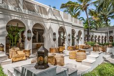 an outdoor seating area with palm trees in the background and white stucco walls on both sides