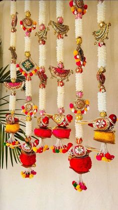 a bunch of different colored beads hanging from a ceiling next to a potted plant