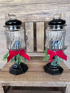 two glass salt and pepper shakers with red bows on the top, sitting on a wooden table