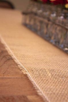 a close up view of the edge of a wooden table with glass vases in the background