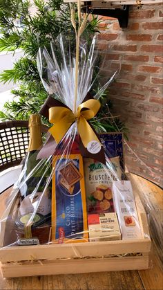 a basket filled with wine and snacks on top of a wooden table