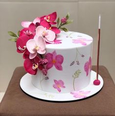 a white cake with pink flowers on it and a stick sticking out of the top