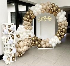 a large balloon arch is decorated with gold and white balloons