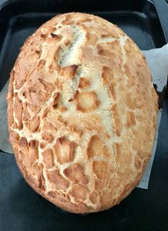 a round loaf of bread sitting on top of a black tray next to a knife