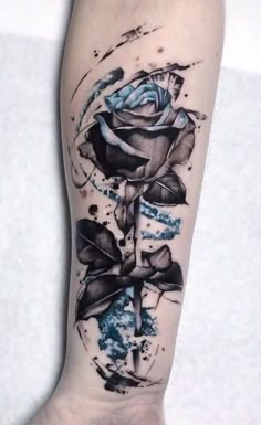 a black and white rose tattoo on the right arm, with blue ink splatters