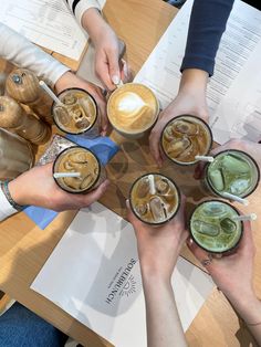 several people are holding cups with drinks in them