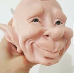 a person holding up a fake troll mask to their face with one eye open and the other half closed