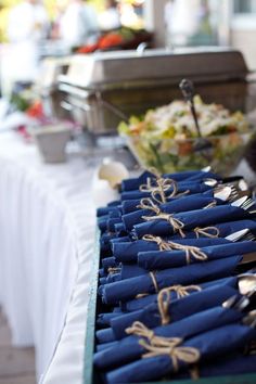 blue napkins tied with twine are lined up on a table at an event