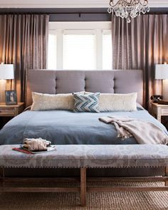 a bedroom with a large bed and chandelier hanging from the ceiling above it