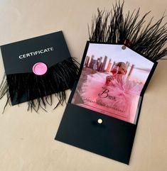 a black and pink photo frame sitting next to a card with a feather decoration on it