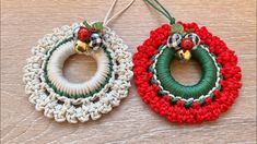 two crocheted christmas wreaths with bells hanging from strings on a wooden surface