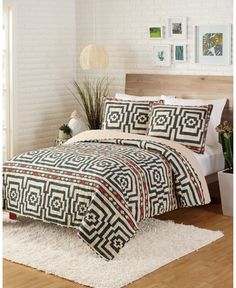 a bed with a black and white quilt on top of it next to a potted plant