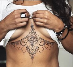 a woman with a rose tattoo on her stomach is holding something in her hand and looking at the camera