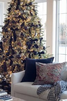 a living room with a christmas tree in the corner and lots of pillows on the couch