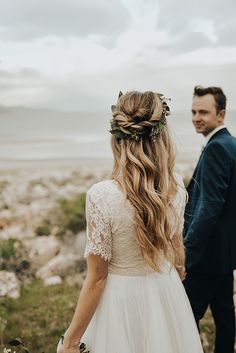 a man and woman standing next to each other in front of the ocean with long hair