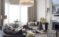 a living room filled with furniture and a chandelier hanging from the ceiling over a fire place