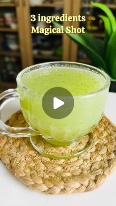 a cup filled with green liquid sitting on top of a woven basket next to a plant