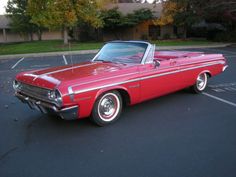 an old red car parked in a parking lot