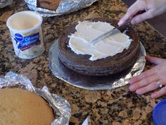 someone is cutting into a cake with white frosting on the top and brown icing on the bottom