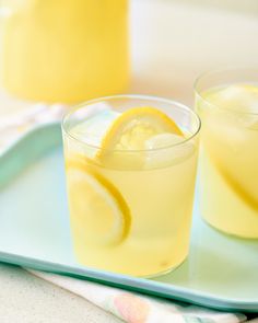 two glasses filled with lemonade sitting on top of a blue tray