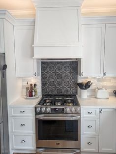 a stove top oven sitting inside of a kitchen next to white cupboards and drawers