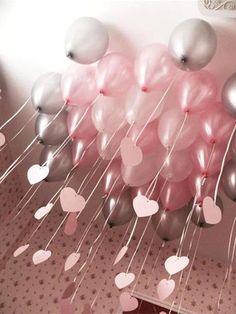 pink and silver balloons floating in the air with hearts attached to them on a string