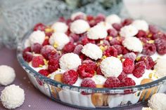 a dessert dish with raspberries and white cream