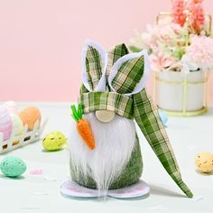 an easter bunny with a green bow and carrot on it's head is sitting in front of some decorated eggs